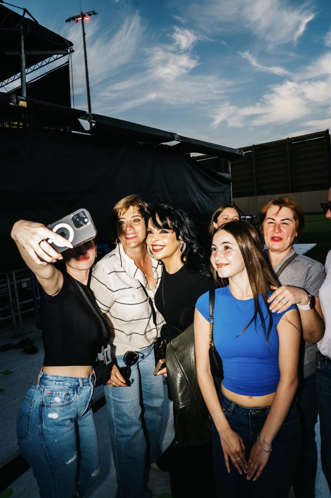 Multi-generational fans taking a selfie with a host backstage